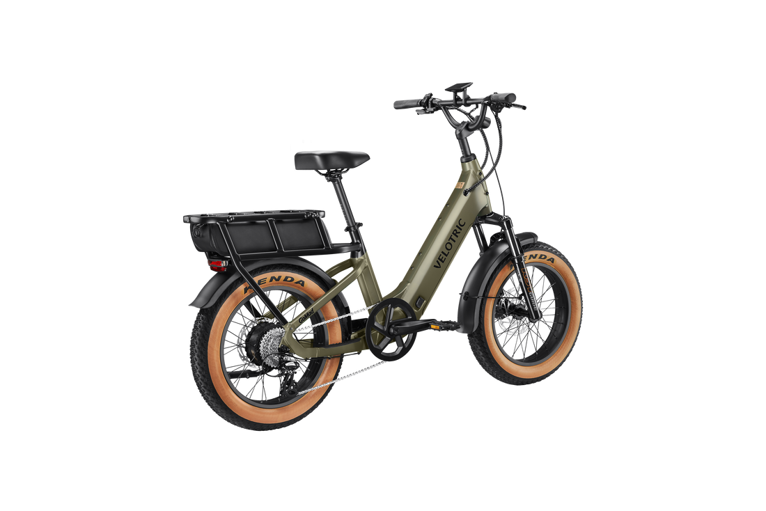 Velotric GoMad electric utility bike riding through city streets with 20″ × 4.0″ fat tires and integrated LED lighting for commuting.