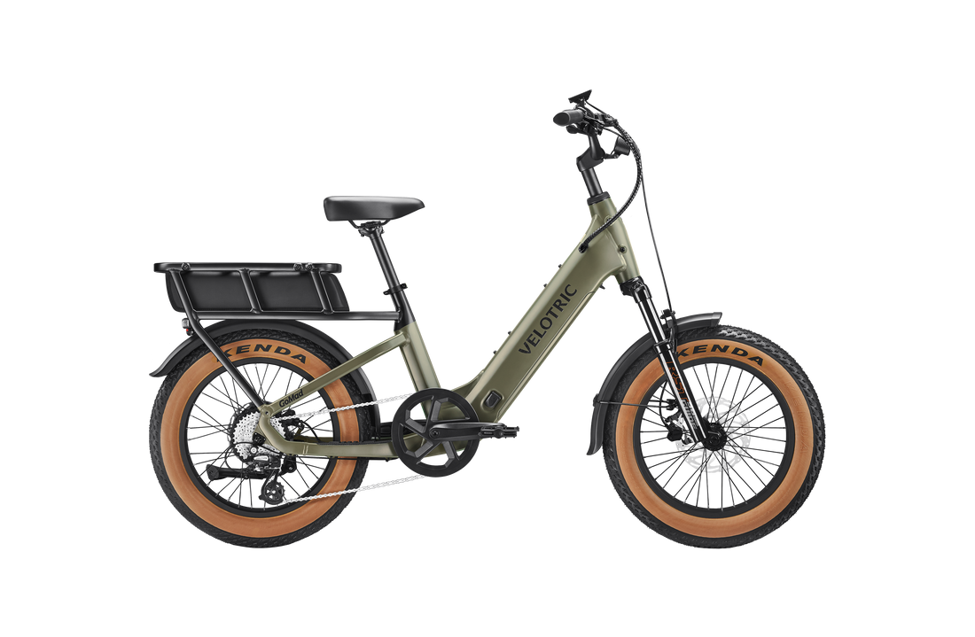 Velotric GoMad electric utility bike riding through city streets with 20″ × 4.0″ fat tires and integrated LED lighting for commuting.