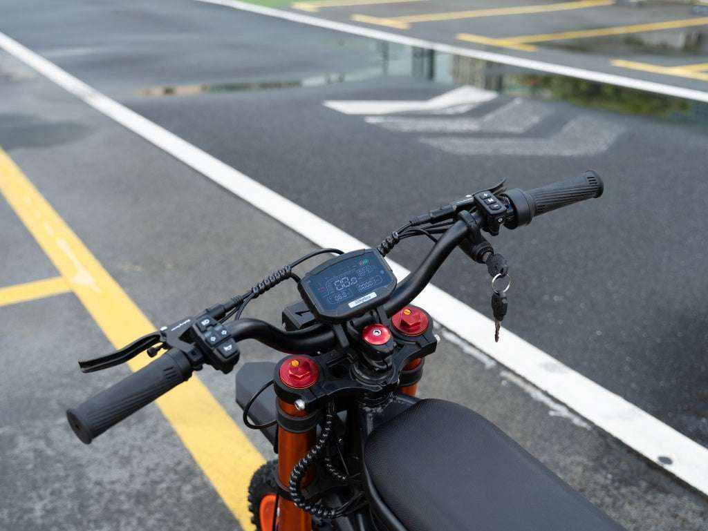 GT54 Electric Mini Motorbike black handles with digital display, red suspension components, and black seat on asphalt road