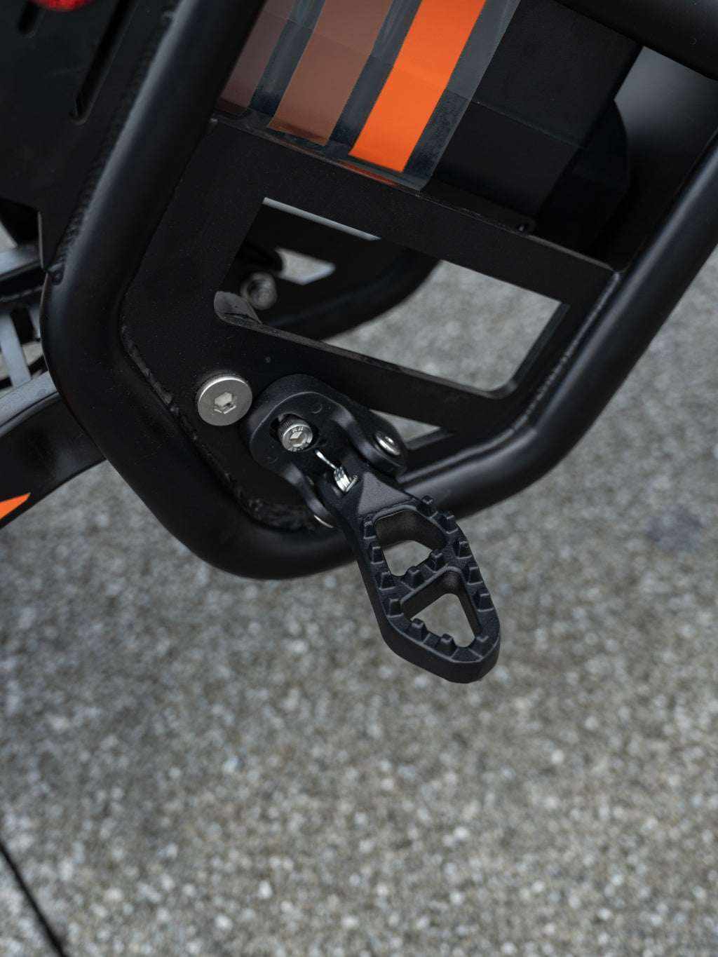 GT54 Electric Mini Motorbike close-up of black metal footpeg and frame detail with orange stripe accents