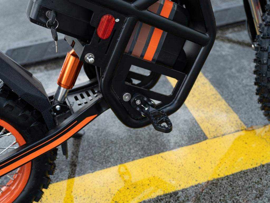 GT54 Electric Mini Motorbike black and orange frame with rugged tires and metal foot pedal close-up detail
