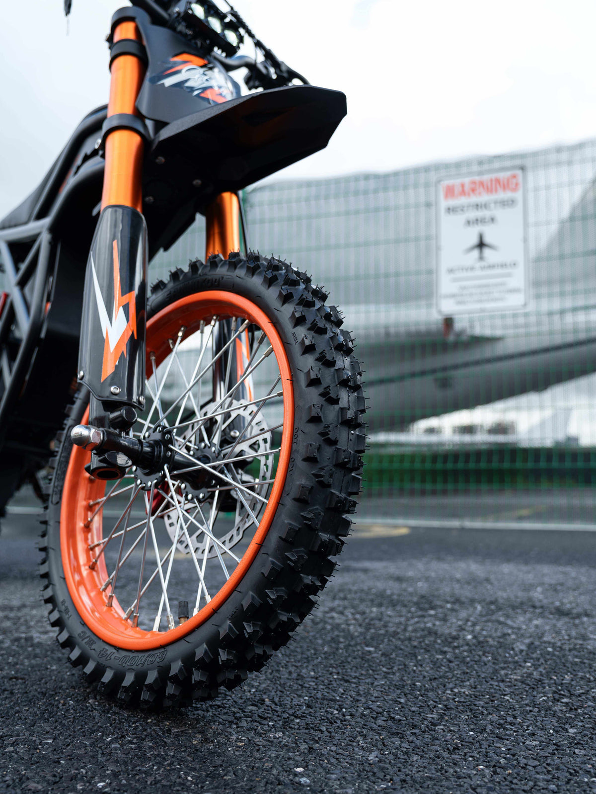 GT54 Electric Mini Motorbike with black and orange frame, knobby off-road front tire, and sporty decals on suspension forks