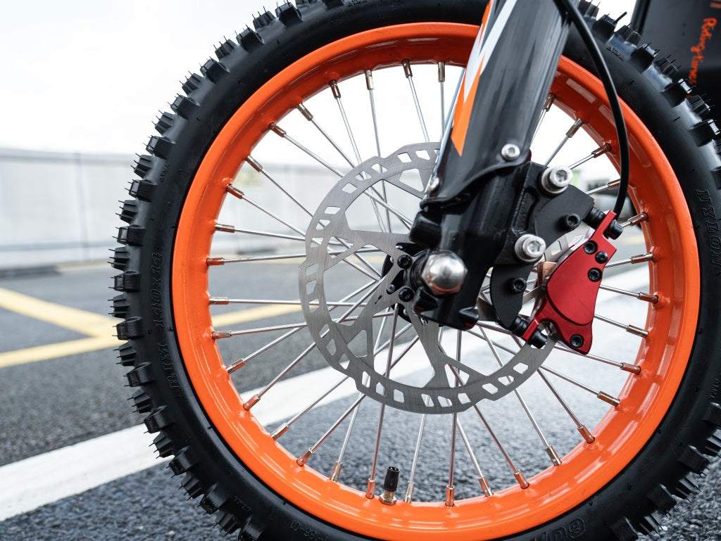 GT54 Electric Mini Motorbike front wheel with bright orange rim, black tire with deep treads, silver spokes, and disc brake