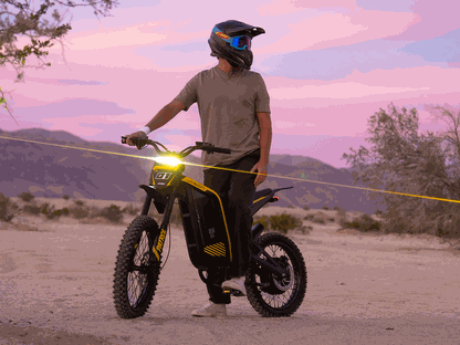 Jasion Patrol 52 electric dirt bike in black and yellow with rugged tires and full suspension, powered on with headlight glowing