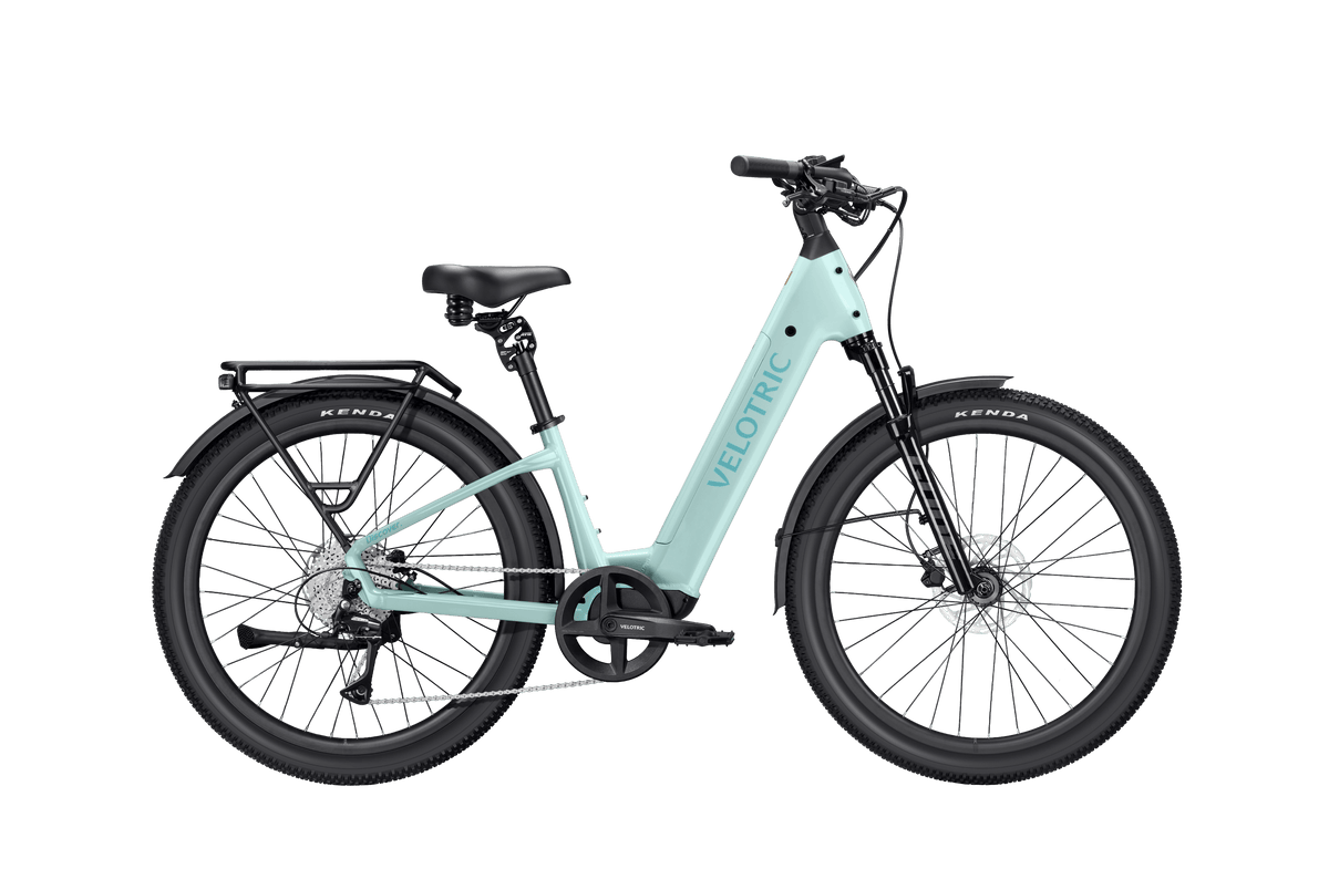 Velotric Discover 3 electric bike in light blue with black accents, step-through frame, hydraulic disc brakes, and rear rack