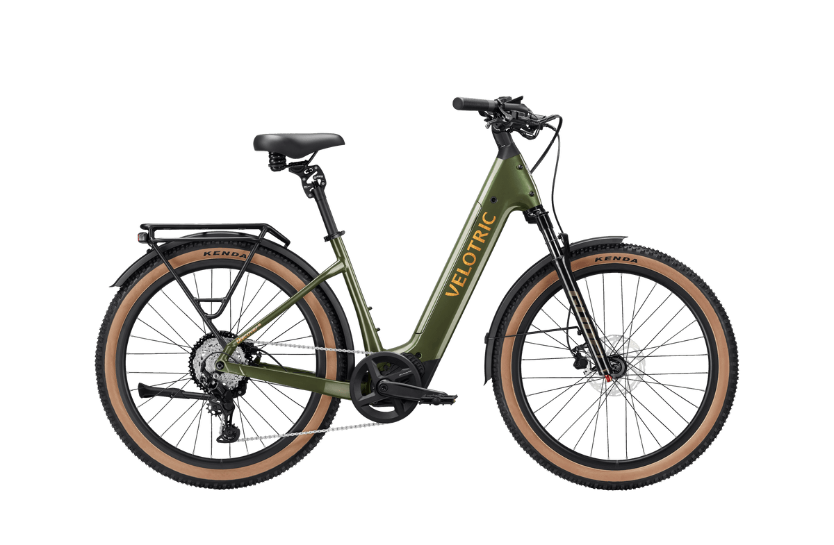 Velotric Discover 3 electric bike in olive green with tan tires, step-through frame, rear rack, and hydraulic disc brakes