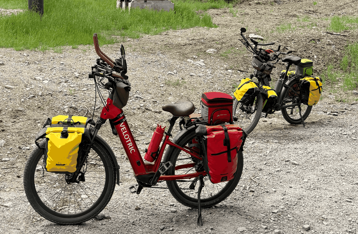 Velotric Discover 3 red electric bike with brown saddle, yellow and red panniers, and handlebar accessories, designed for long rides